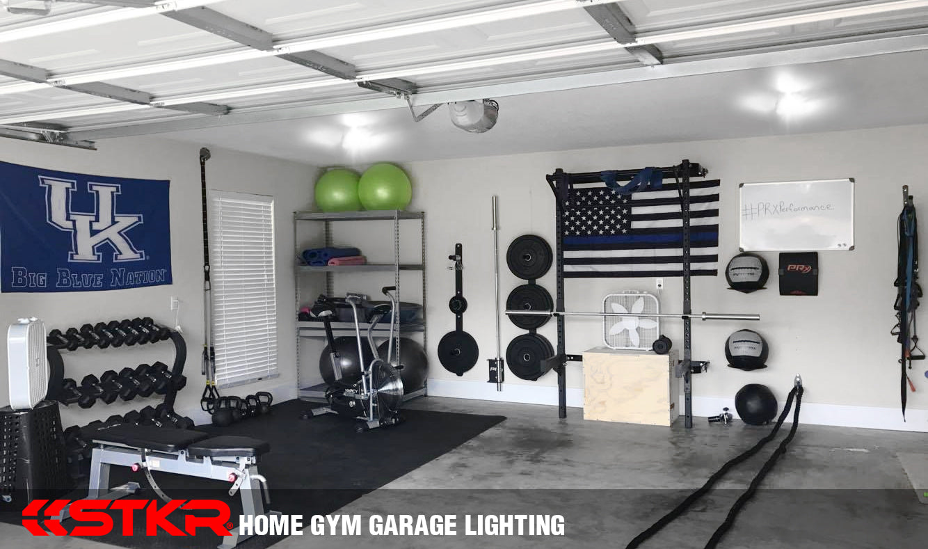 Very well done garage gym illuminated by multiple TriLights by STKR Concepts. Gym features weighted ropes, a squat rack, a free weights station, an elliptical, weighted medicine balls, weight bench, and many, many more.