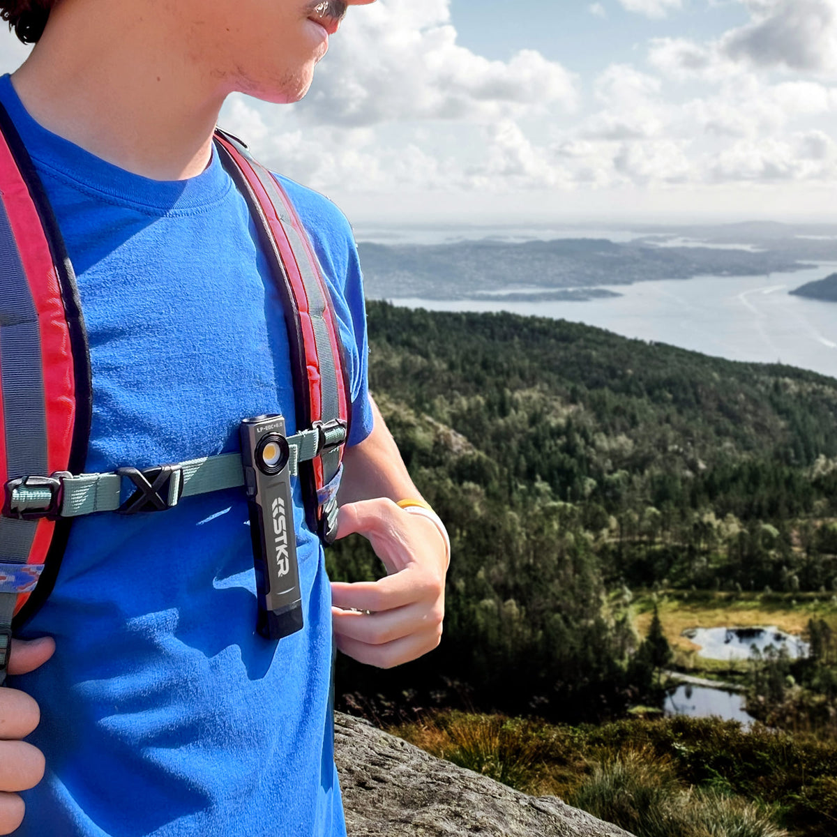 LP-EDC+ 8.0 Low Profile Everyday Carry Ultra-Thin Spot & Flood Flashlight clipped onto a backpack strap of a male hiker on a mountain area over looking beautiful scenery