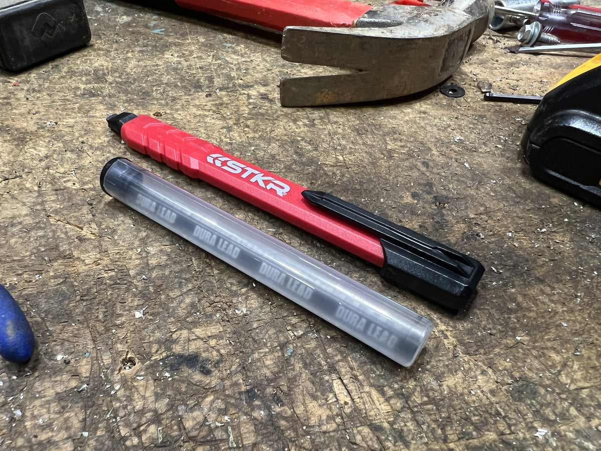 STKR Mechanical Carpenter Pencil next to a DURA Lead refill tube on a workbench