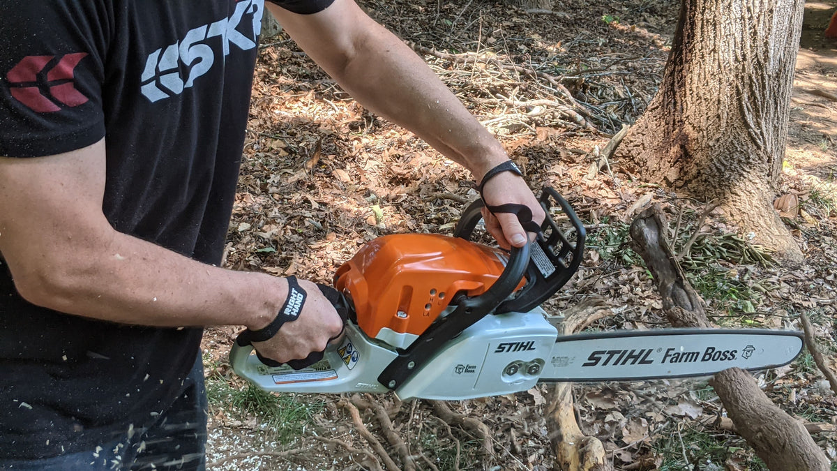 Palm Protectors worn on both hands running a chainsaw in the woods