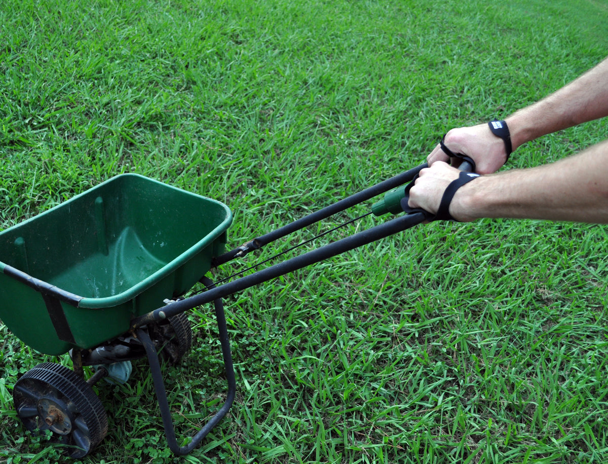 Palm Protectors worn while pushing a lawn spreader across grass